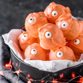 Monster Halloween Truffles! These adorable Halloween truffles are filled with sweet pumpkin cheesecake and coated in festive orange candy. A fun creepy treat for the holidays! | HomemadeHooplah.com