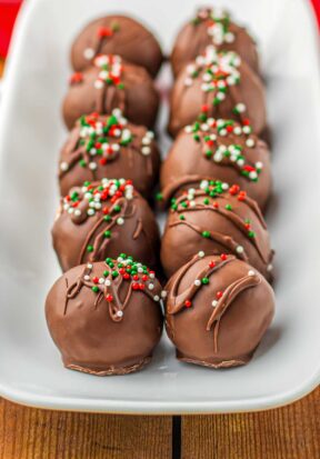 Side view of a tray filled with two rows of prepared and freshly decorated buttercream truffles.