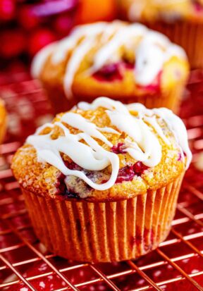 Close up side view of a cranberry orange muffin topped with cream cheese glaze.